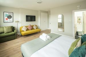 a bedroom with a bed and a yellow couch at Huge Modern 3 Bed Flat Central For Sightseeing in London
