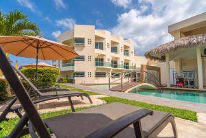 un patio con sombrilla y sillas junto a un edificio en Artisan Playa Esmeralda Family Beach Hotel, en Chachalacas