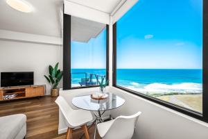 a living room with a glass table and a view of the ocean at Seaside Luxe - L8 - Local Eats, Walks, Swims, CBD in Newcastle