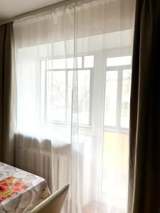 a window with white curtains and a laptop on a table at Центр, 2х комнатная студио возле парка, WIFI in Vinnytsya