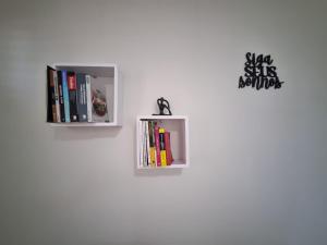 two shelves on a wall with books at Espaço do acalanto- Quarto em apartamento compartilhado in Natal