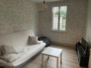 a living room with a white couch and a table at Gîte centre coulon - Le Héron in Coulon