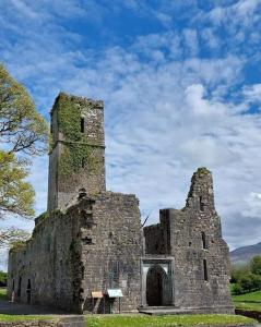 an old stone building with a tower on a field at Mountain View in Tipperary