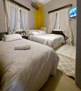 a bedroom with two beds and a flat screen tv at jim villa family apartment with private yard andravida-kyllini in Andravída