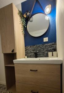 a bathroom sink with a mirror on a blue wall at Studio - Le Cocon in Saint-Brieuc