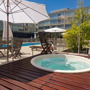 a hot tub on a deck with chairs and an umbrella at iDeal Concord Pilar Aparts in Pilar