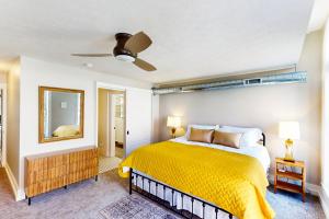 a bedroom with a yellow bed and a mirror at 'Downtown Delight' w/ Patio! 1 Mi to Ball State in Muncie