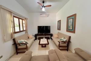 a living room with a couch and a tv at Refúgio na natureza com piscina e churrasqueira in Pedro de Toledo