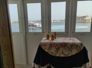 a table in a room with windows with a view of the water at SeaFront Apartment In Valletta in Valletta