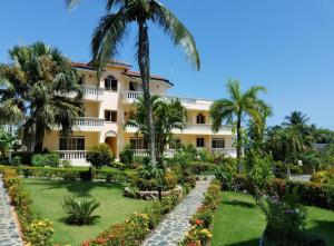 a large yellow building with palm trees and a garden at Casa Lio, Caribbean Pool Residence in Boca Chica