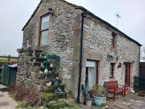 an old stone house with a bench in front of it at Old Coach House in Matlock