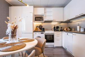a kitchen with white cabinets and a table with chairs at Coastal Wooden Apartment Rauma in Rauma