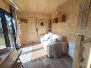 a living room with a white couch in a wooden wall at chalet bohème au calme in Saint-Ambreuil