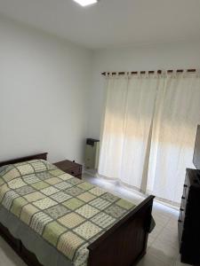 a bedroom with a bed and a window with curtains at Departamento Plumerillo in Santa Rosa +2 photos