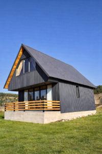 a black house with a black roof on a green field at Eternum Glamping in Žabljak
