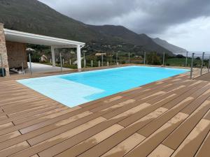 a large blue swimming pool with a wooden deck at Villa Orizzonte in Scopello