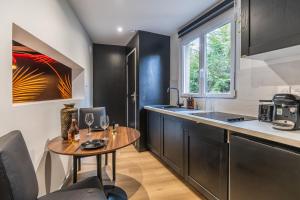 a kitchen with black cabinets and a wooden table at La Cachette - Suite romantique & balnéo privative in Hermeray