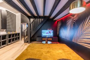 a living room with a staircase and a television at La Cachette - Suite romantique & balnéo privative in Hermeray
