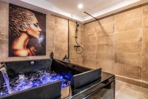 a bathroom with a tub with a picture of a woman at La Cachette - Suite romantique & balnéo privative in Hermeray