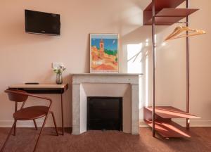 a living room with a fireplace and a desk and a tv at Hotel Louvia in Menton