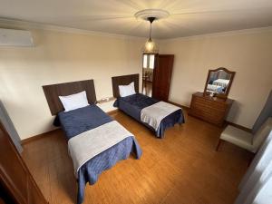 a bedroom with two beds and a mirror at Casa dos Neto Carriço in Anadia