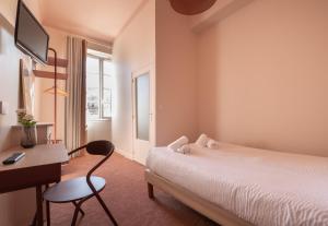 a bedroom with a bed and a desk and a chair at Hotel Louvia in Menton
