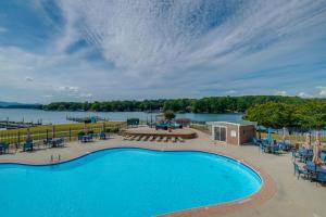 a swimming pool with tables and chairs next to a lake at Surfboard-Themed Huddleston Studio w/ Beach Access in Huddleston