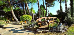 a garden with a wooden bridge with plants and trees at Hotel Garden in Nuraminis
