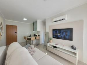 a living room with a white couch and a tv at GALILEU - Apartamento próximo à UniCPO, Mondelli, USP, FACOP e FIASP in Bauru