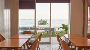 a restaurant with tables and chairs and a view of the ocean at Klinakis Beach Hotel in Chania
