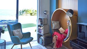a woman sitting in a hanging chair reading a book at Klinakis Beach Hotel in Chania