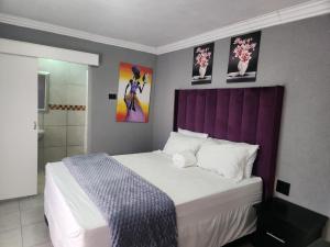 a bedroom with a large bed with a purple headboard at Kiba guest house in Marble Hall