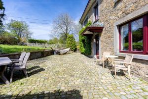 a patio with chairs and a table and a building at Ferme du Banoyard in Theux