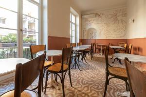a dining room with tables and chairs and windows at Hotel Louvia in Menton