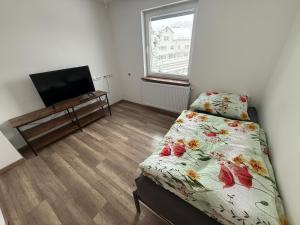 a bedroom with a bed and a flat screen tv at Schelder Zimmer in Dillenburg