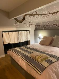 a bedroom with a bed with a tree painted on the ceiling at La P'tite Bicoque in Doizieux +10 photos