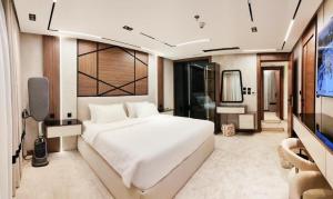 a bedroom with a large white bed and a flat screen tv at فلل خاصة في آي بي فاخرة - فندق وأبراج مكة in Mecca