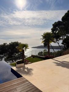 a pool with palm trees and a view of the water at Blueview Villa in Llafranc