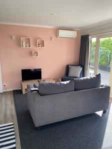 a living room with a grey couch and a tv at Property close to the beach in Nelson