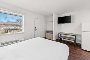 a white bedroom with a bed and a desk at Birch Hill Suites Kansas City - Independence in Independence
