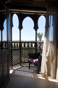 a room with a balcony with a chair and windows at Le Temple Des Arts in Ouarzazate