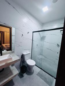 a bathroom with a toilet and a glass shower at Pousada Parque do Lago in Sinop