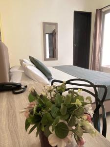 a vase of flowers sitting on top of a bed at HOTEL CATALUÑA PEREIRa in Pereira