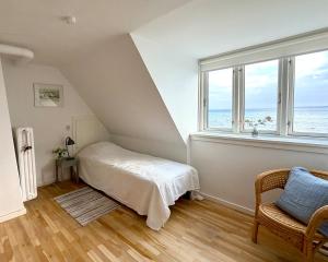 a bedroom with a bed and a large window at Beachhouse Humlebæk in Humlebæk