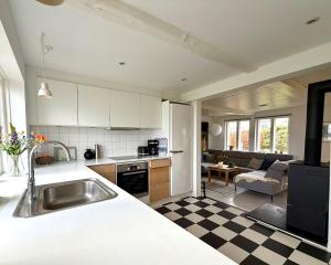 a kitchen with a sink and a living room at Beachhouse Humlebæk in Humlebæk