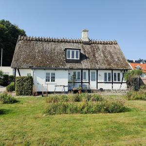a white cottage with a thatched roof at Beachhouse Humlebæk in Humlebæk