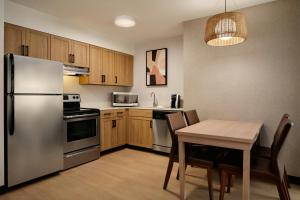 a kitchen with a table and a stainless steel refrigerator at Residence Inn Phoenix Mesa in Mesa