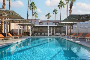 a swimming pool with chairs and umbrellas at Residence Inn Phoenix Mesa in Mesa