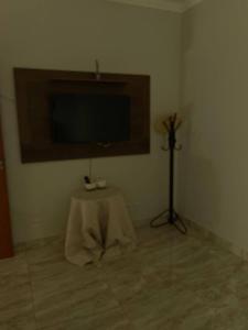 a room with a table and a flat screen tv at Pousada e Edícula in Jabuticabal