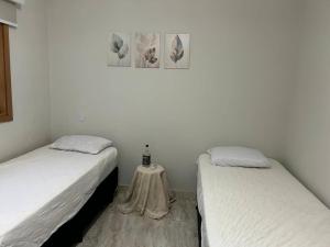 two beds in a room with a small table between them at Pousada e Edícula in Jabuticabal +21 photos